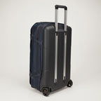 A dark navy blue hard-shell carry-on suitcase with an extended silver telescopic handle and dual spinner wheels, shown on a light gray studio background.